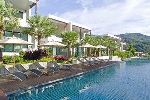 Relax by the pool surrounded by lounge chairs and umbrellas on a spacious deck.
