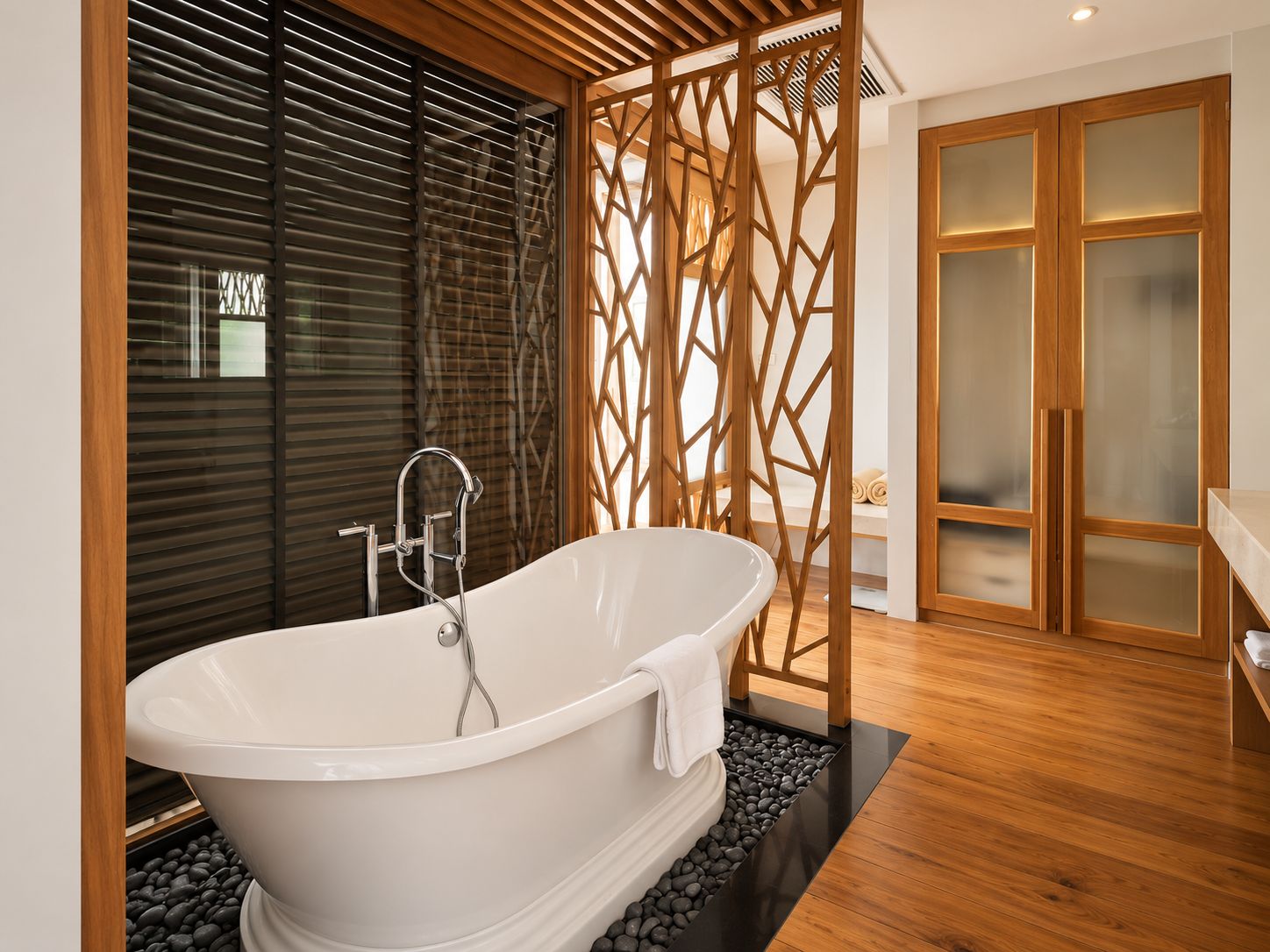 A modern bathroom with a freestanding bathtub, wooden floor, and a glass-enclosed walk-in closet.