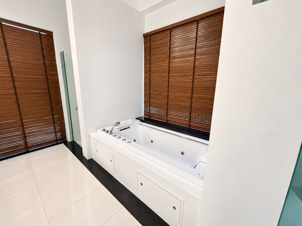 Un baño moderno con una bañera independiente, muebles de color blanco y persianas de madera.