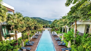 A pool area with lounge chairs and palm trees, surrounded by greenery and a mountain view. - Club Wyndham Patong Hill Phuket, Trademark Collection by Wyndham (Patong)