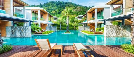 Un complexe hôtelier moderne doté d’une piscine centrale, d’une terrasse en bois et de chaises longues.