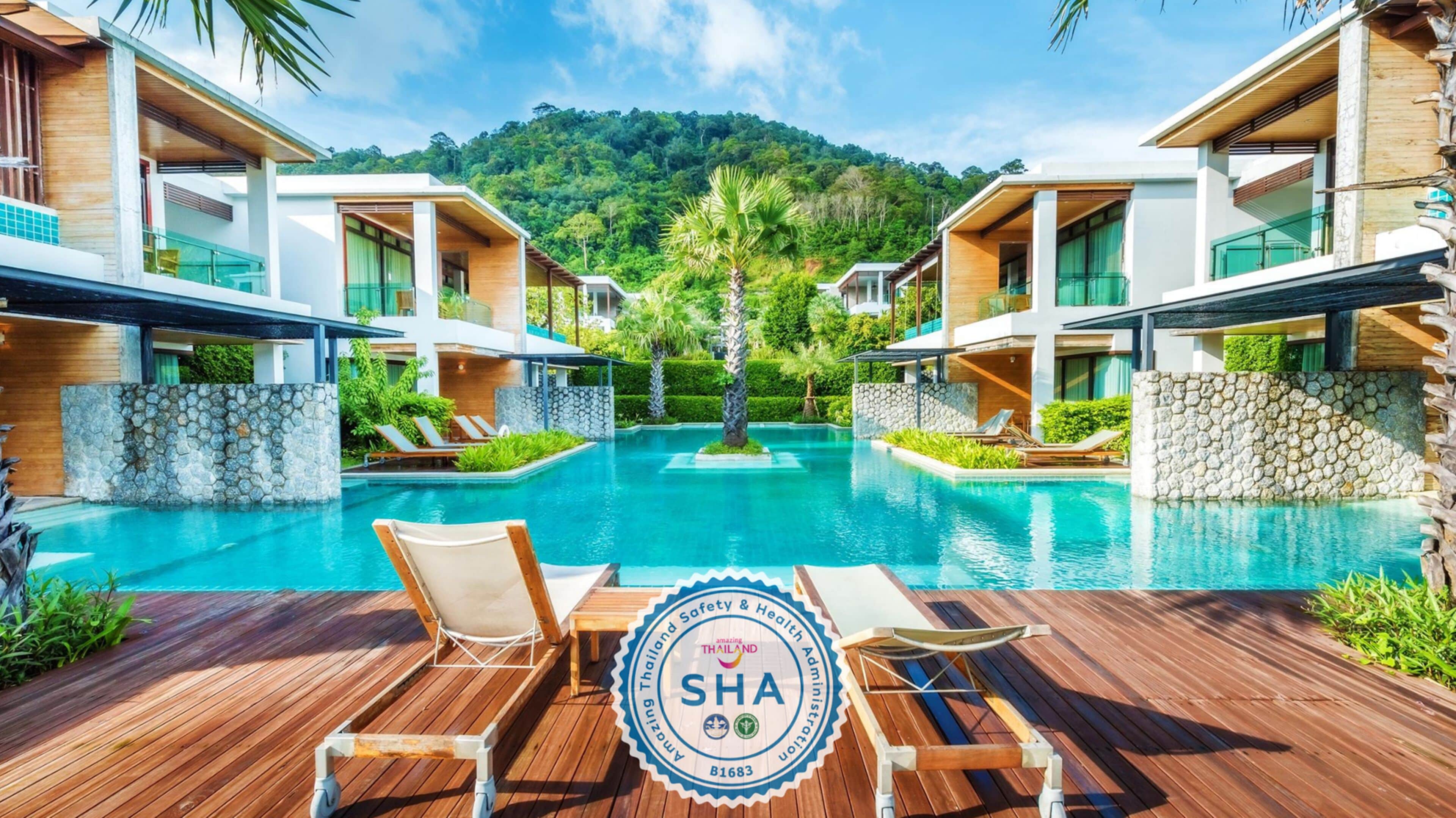 A modern resort with a central pool, wooden deck, and lounge chairs.