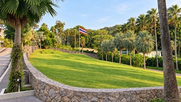 A landscaped area with a stone wall, palm trees, and a flag.