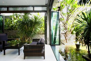 A modern indoor garden with a sofa, coffee table, and potted plants.