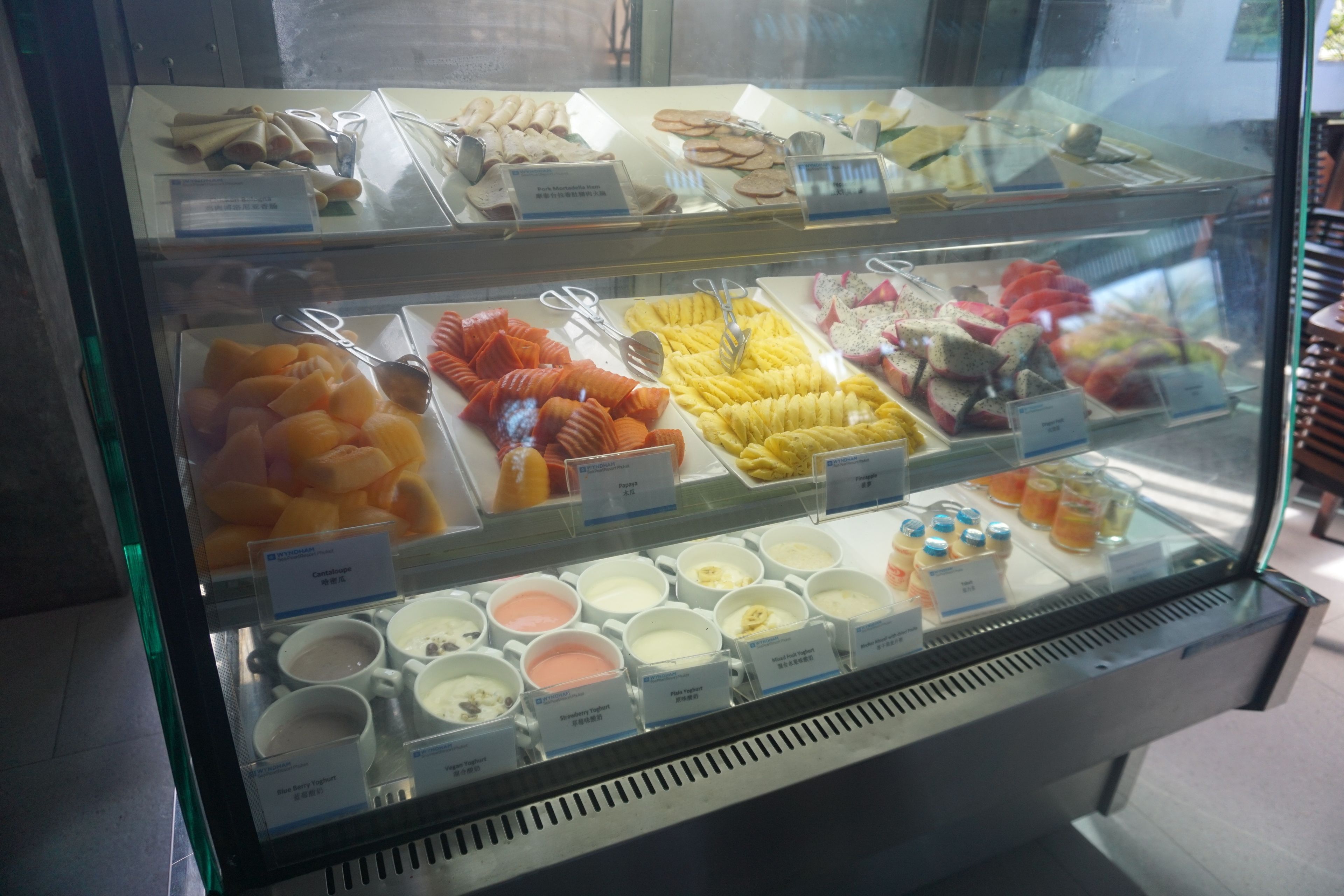 A display case with various food items including fruits, pastries, and desserts.