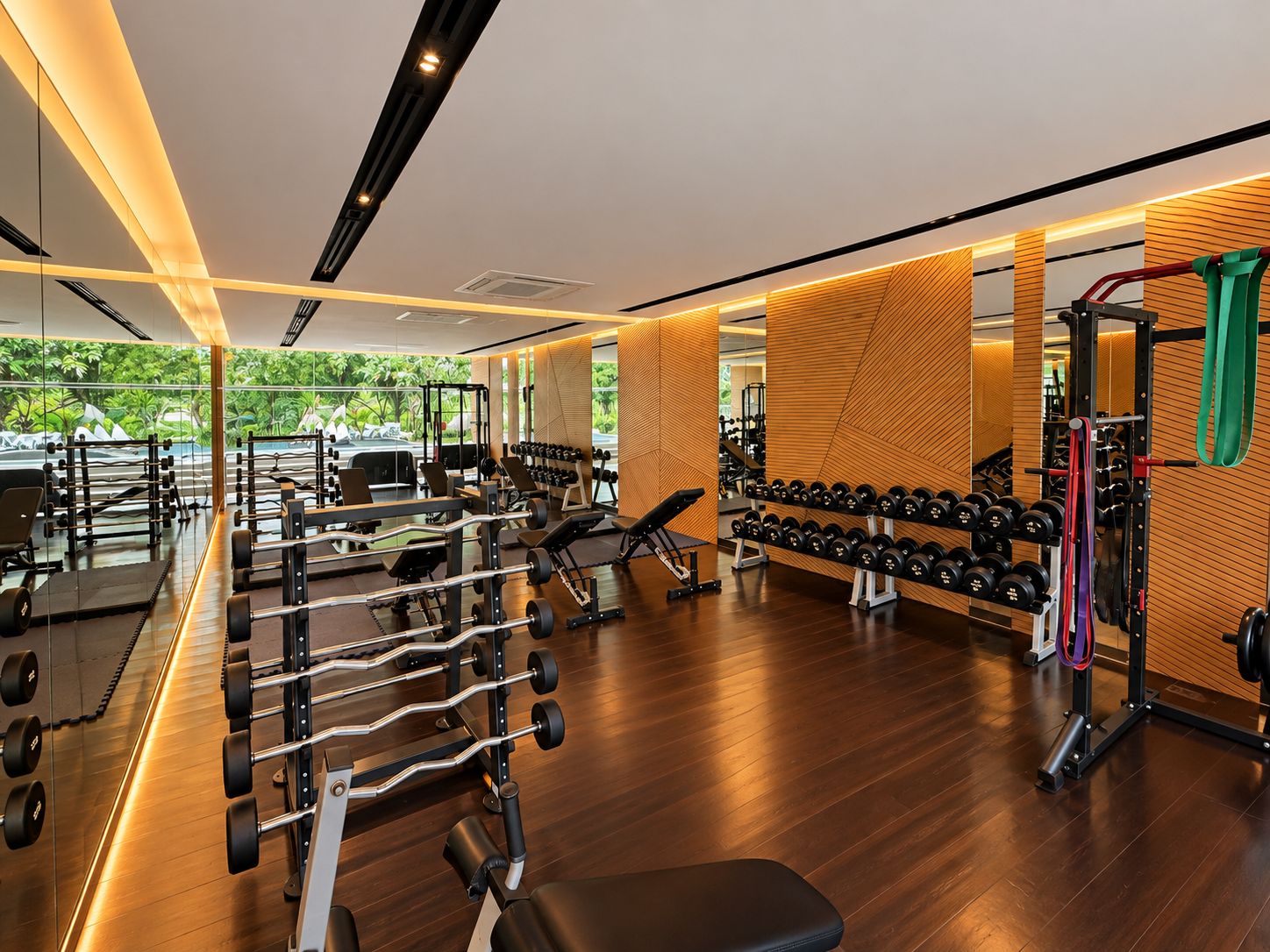 A modern gym with various weightlifting equipment, a bench, and a wall-mounted rack of dumbbells.