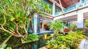 Ein modernes Hotel mit üppigem Garten, einem Teich und einem überdachten Gang.