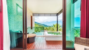 Ein Balkon mit Holzboden, Whirlpool und Blick auf grüne Hügel.