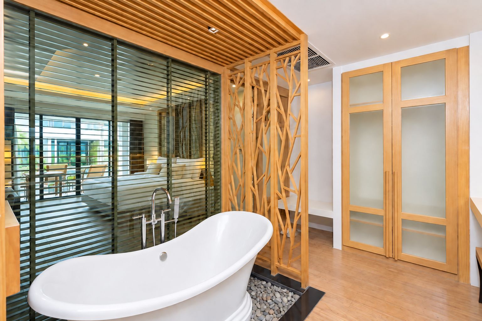 Ein modernes Badezimmer mit einer freistehenden Badewanne, einer Holzabtrennung und einer Duschkabine aus Glas.