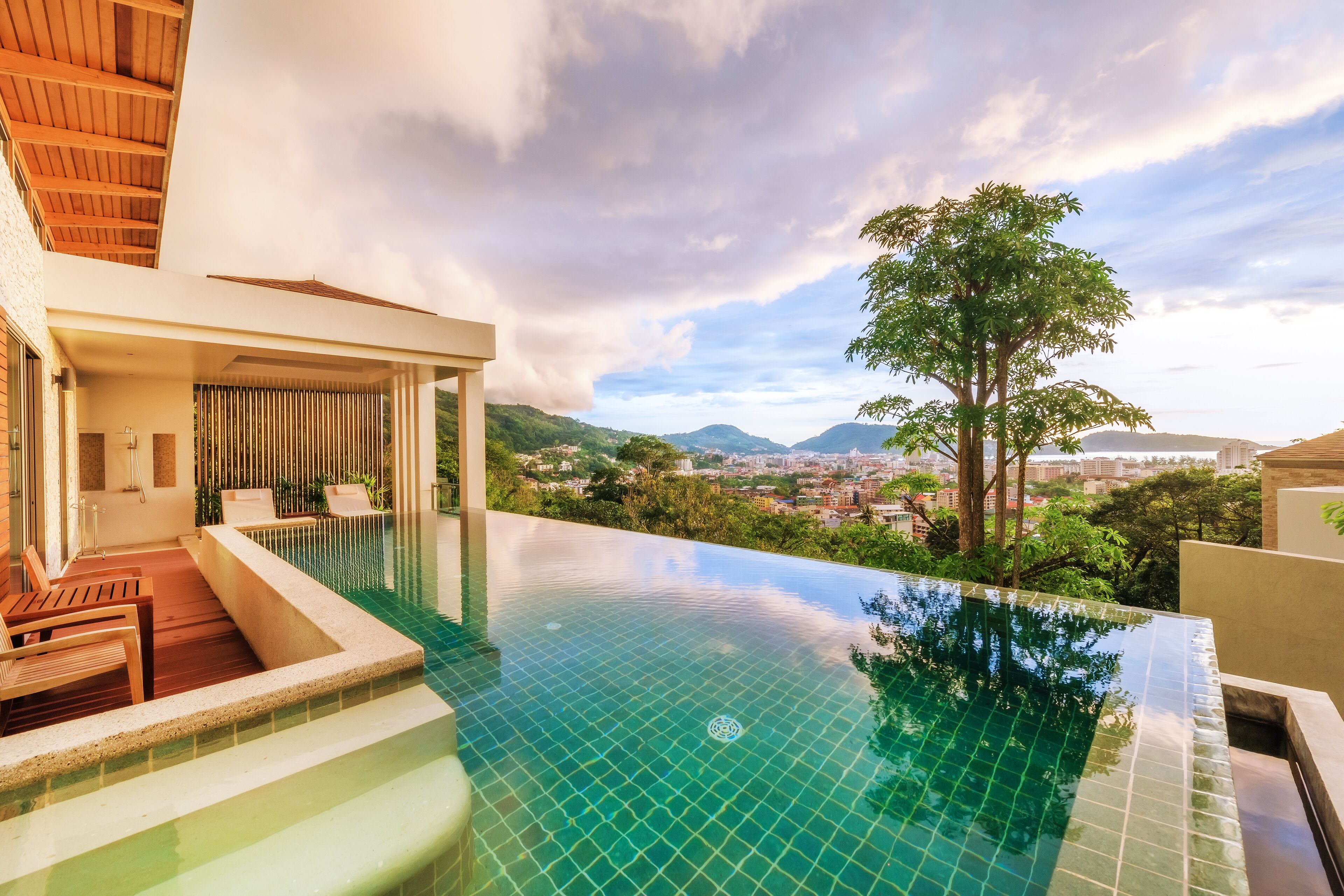 A modern infinity pool with a clear view of the city and mountains in the background.