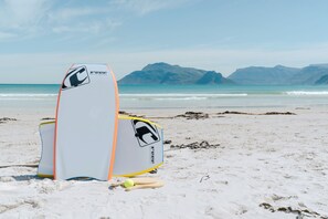 Two surfboards on a sandy beach with mountains in the background. - Last Word Long Beach (Cape Town)