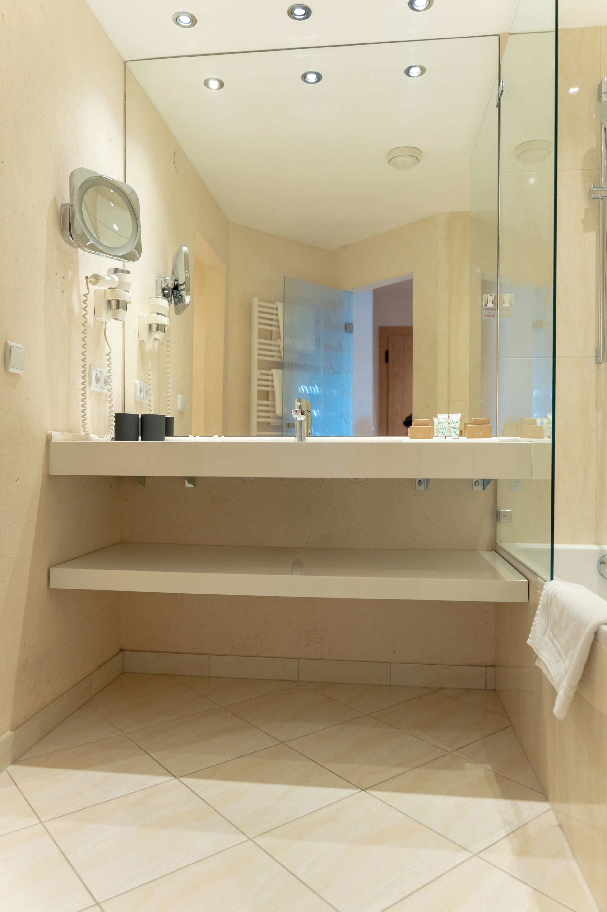 A modern bathroom with a glass shower enclosure, a vanity with a mirror, and a towel rack.