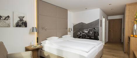 A modern bedroom with a large bed, a bedside table, a chair, and a wall-mounted lamp.