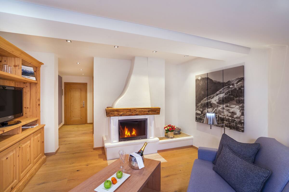 A modern living room with a fireplace, wooden cabinets, a television, and a large landscape painting.