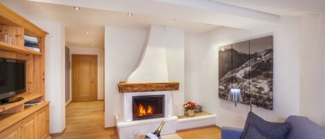 A modern living room with a fireplace, wooden cabinets, a television, and a large landscape painting.