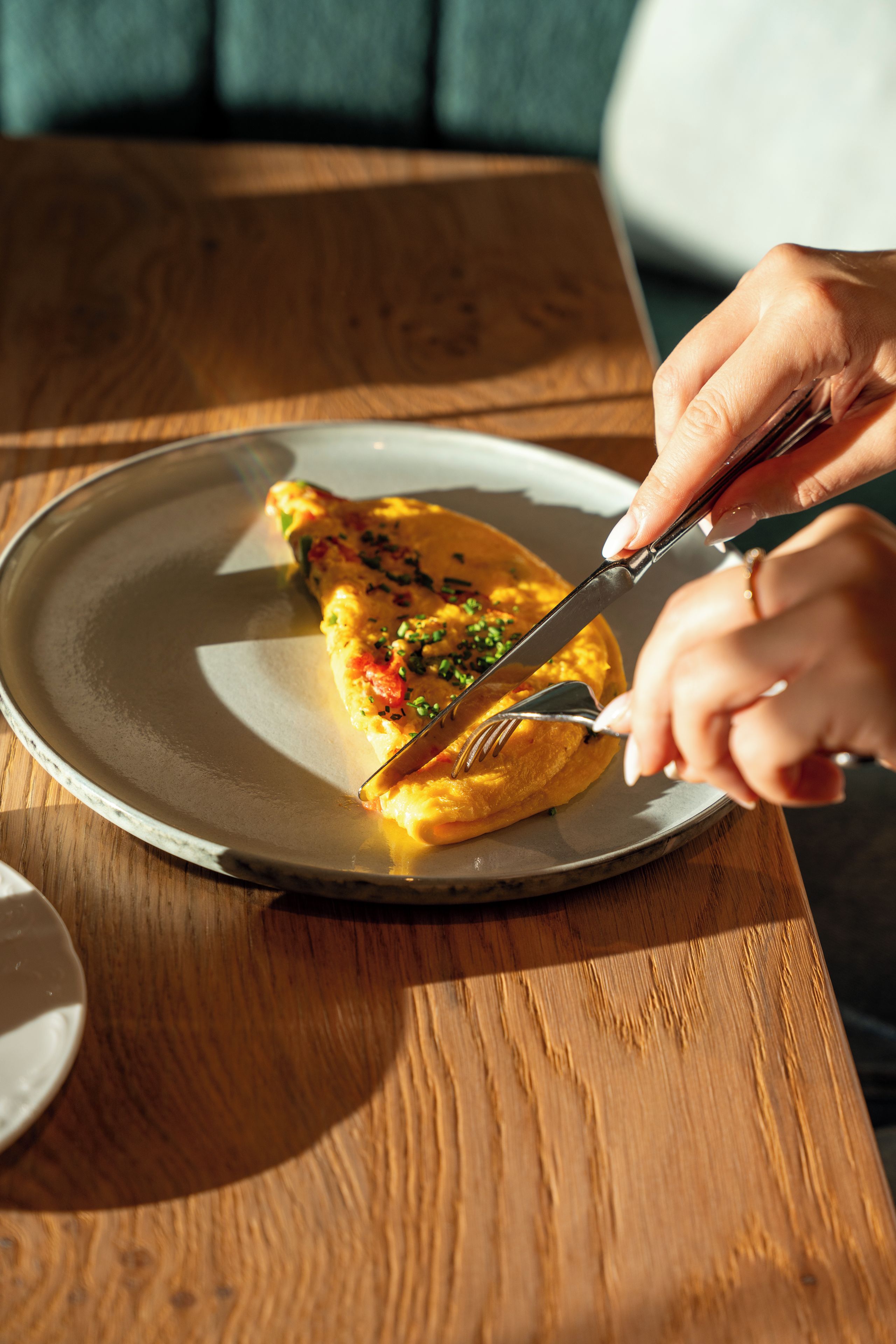 A person cutting a slice of food on a plate.