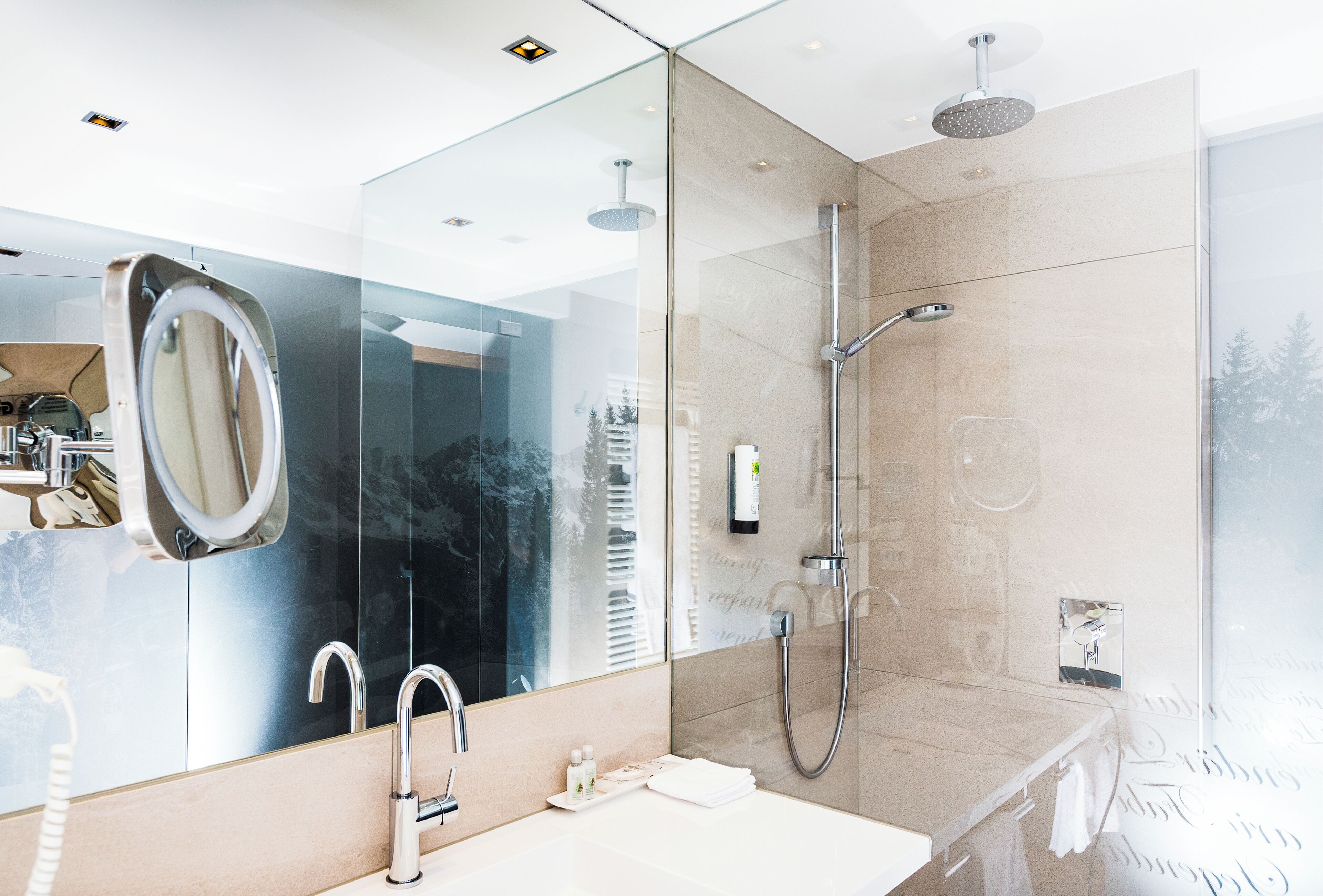 A modern bathroom with a large mirror, a sink, a shower with a handheld showerhead, and a glass-enclosed shower area.