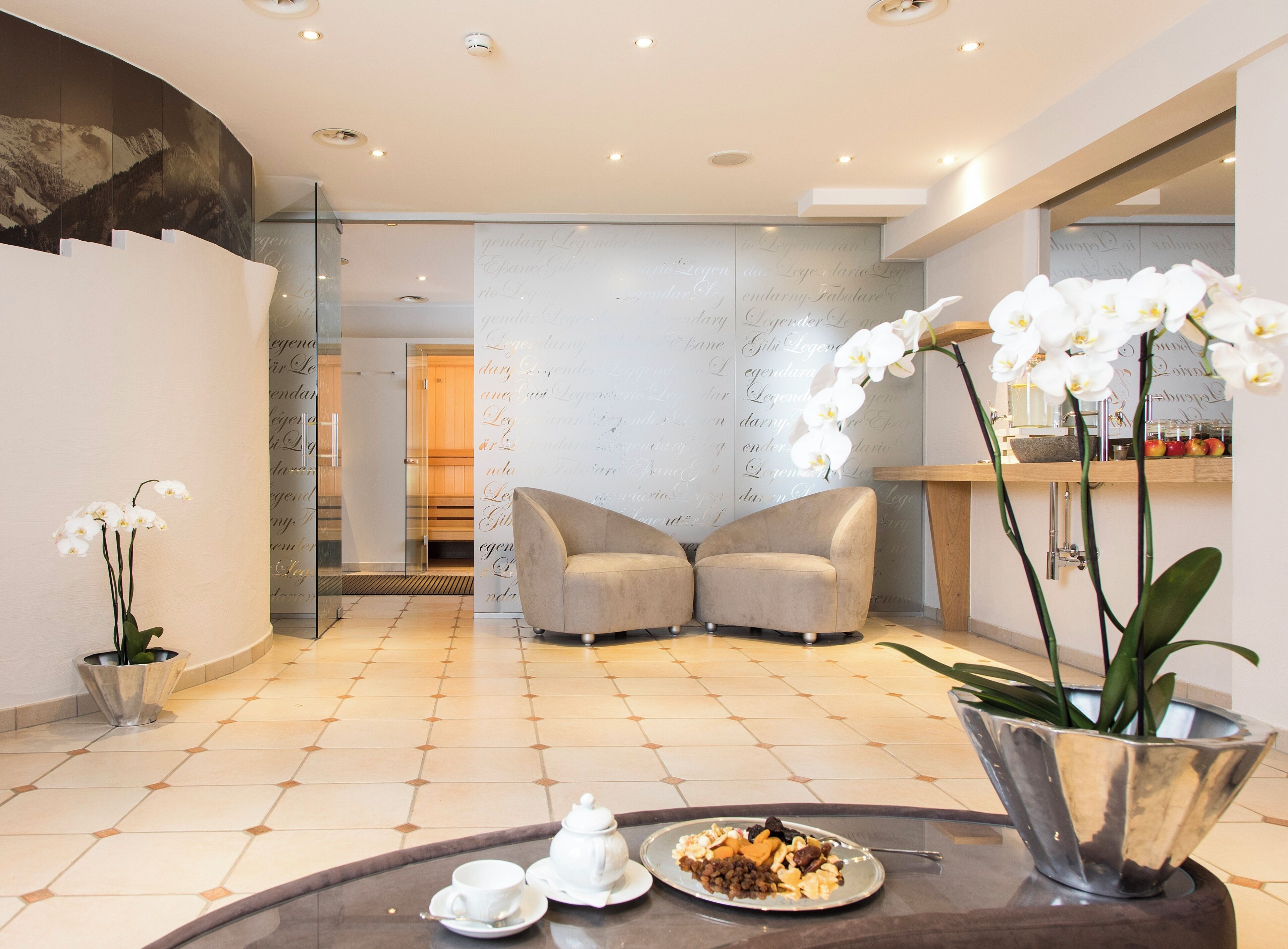 A modern hotel lobby with a seating area, a reception desk, and a decorative wall with text.