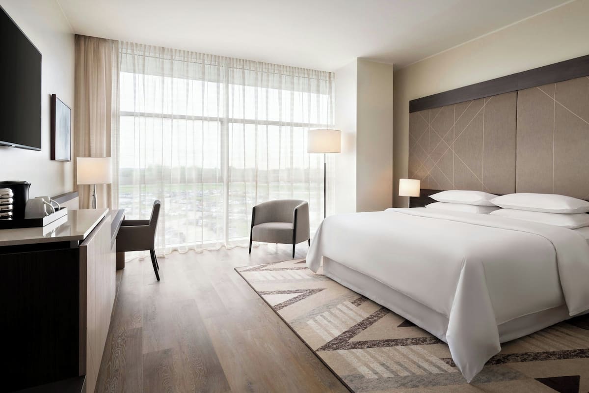 Ein Hotelzimmer mit Bett, Schreibtisch, Stuhl und großen Fenstern.