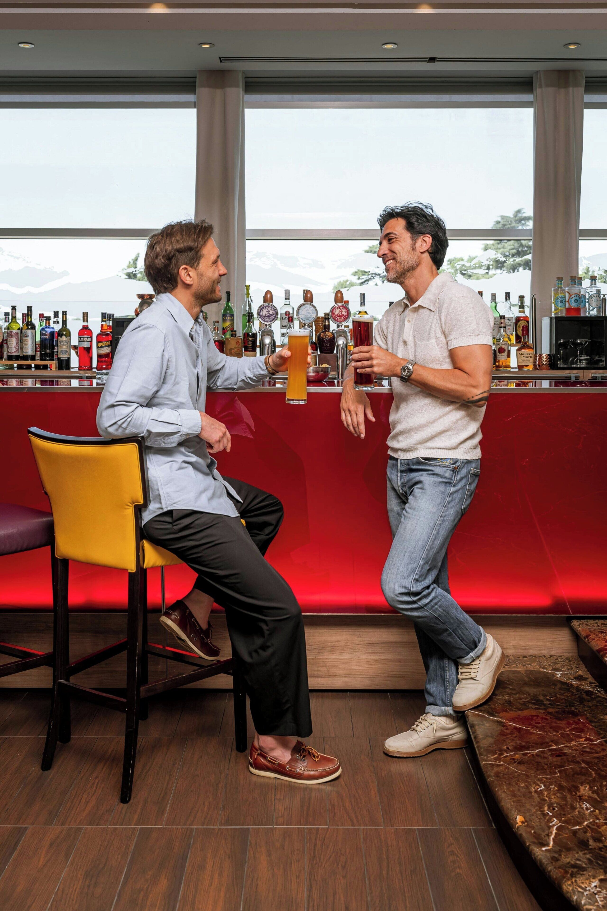 Two men at a bar with a view of mountains.