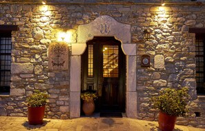 Un edificio de piedra con puerta de madera, dos macetas y un letrero sobre la puerta.