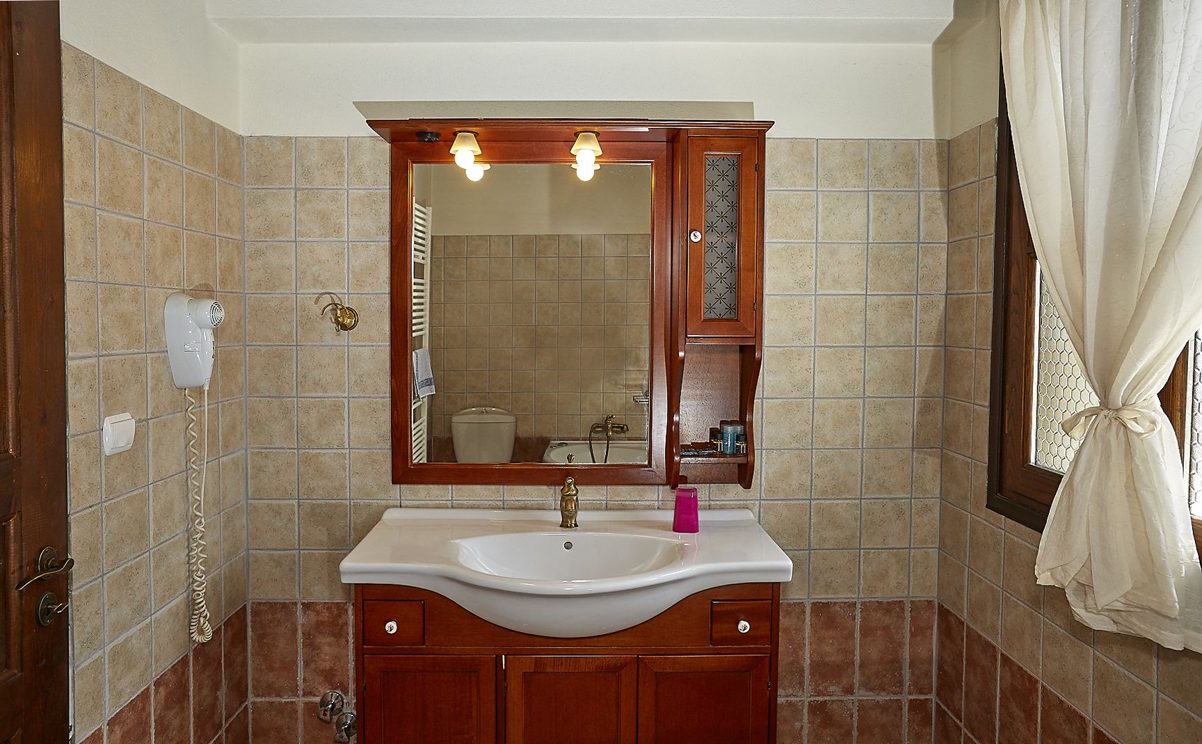 Une salle de bain avec un lavabo blanc, un meuble-lavabo en bois et un miroir au-dessus.
