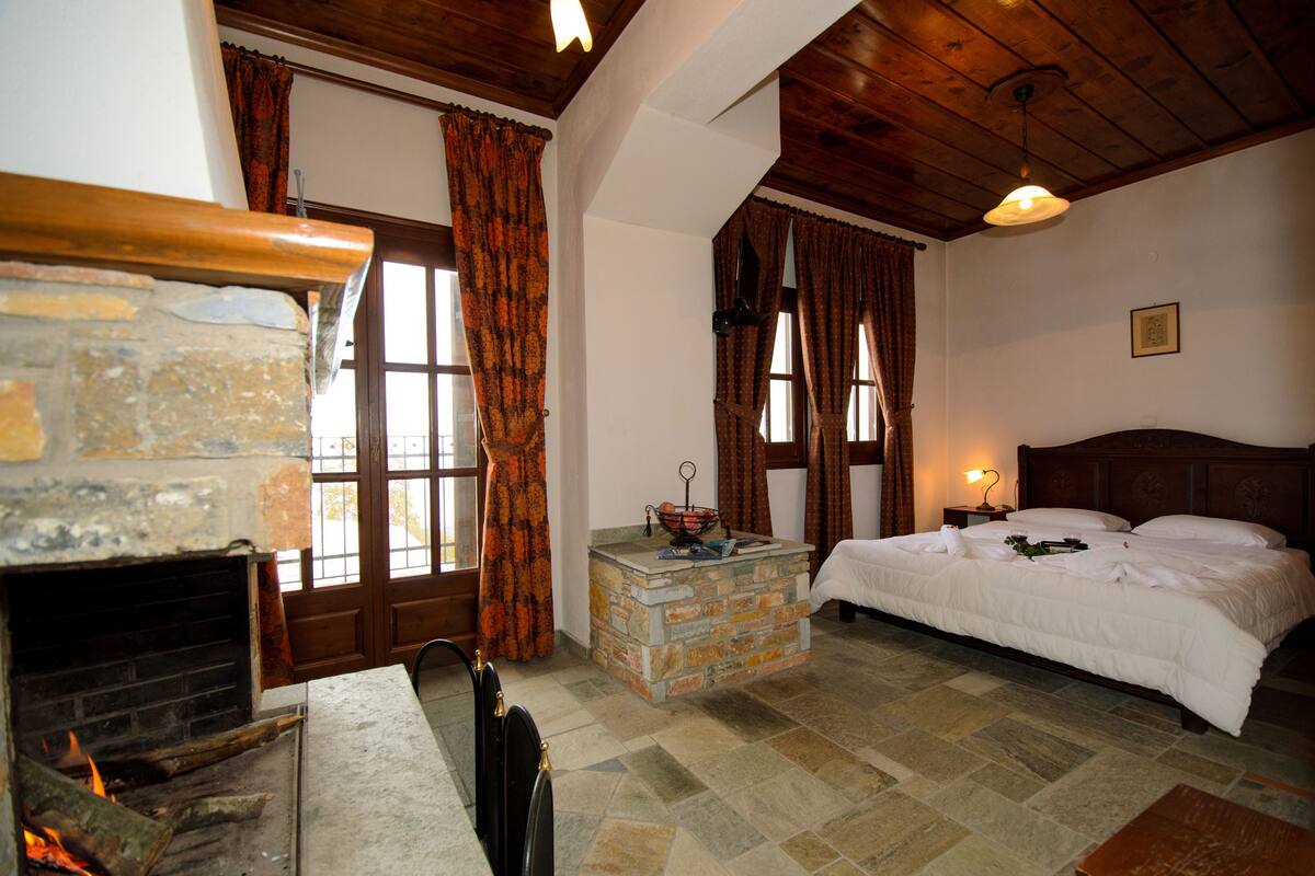A cozy room with a stone fireplace, a bed with white bedding, and a stone coffee table.