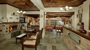 Une auberge traditionnelle avec une cheminée en pierre, des meubles en bois et un sol en pierre.