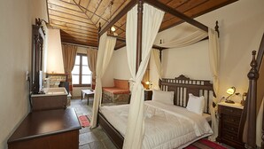 Un lit à baldaquin, une commode en bois, un miroir et une cheminée en pierre.