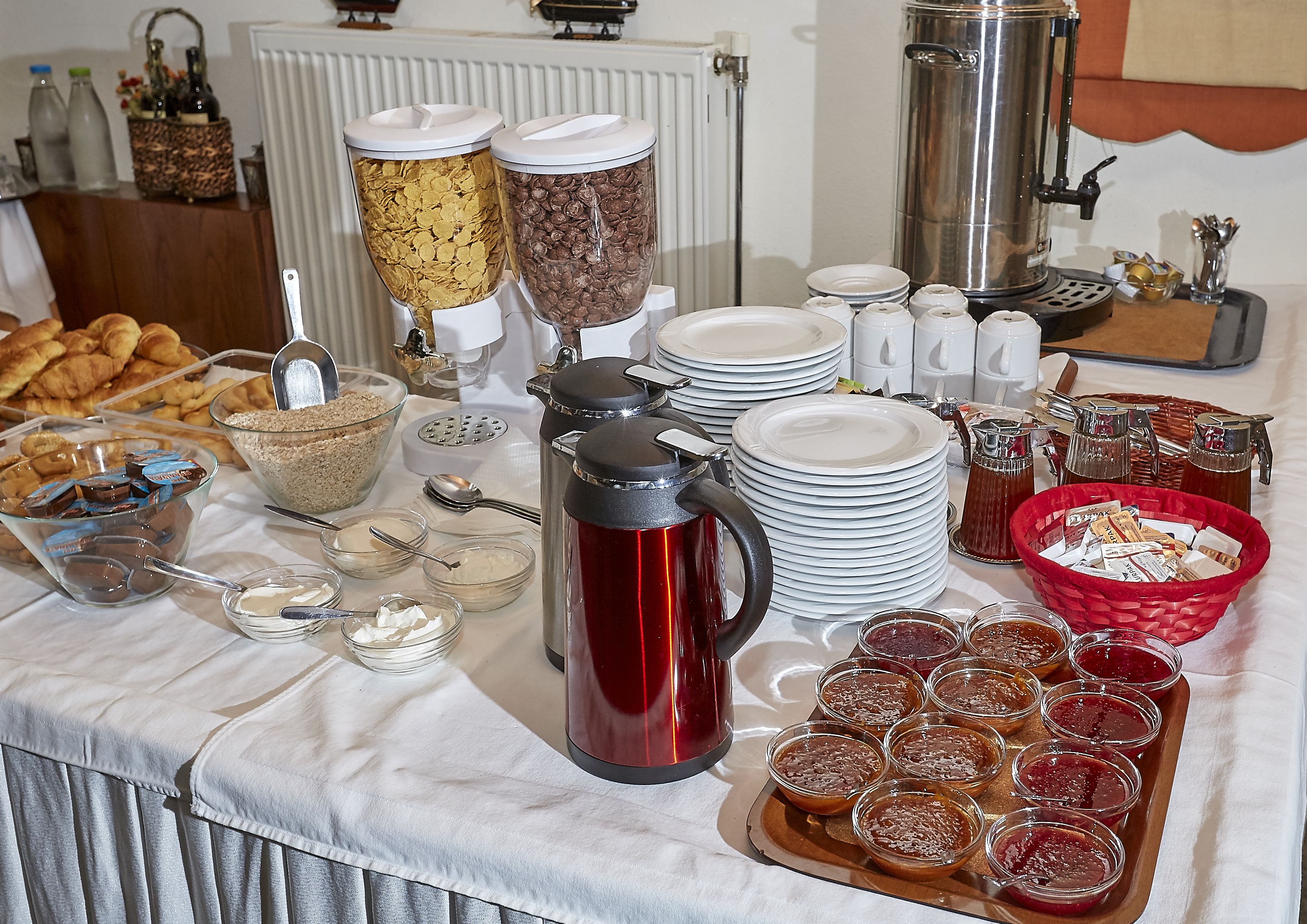 A buffet table with various food items, including cereal, chocolate, and condiments.