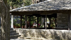 Un bâtiment en pierre avec un toit en tuiles, un escalier en pierre et des plantes en pot.