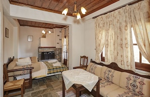 A cozy room with a sofa, a chair, a table, and a fireplace. - Atrapos Hotel (Zagora-Mouresi)
