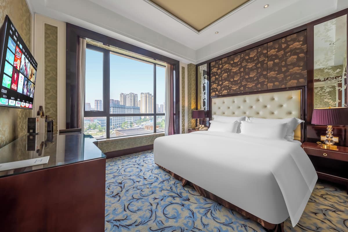 Een hotelkamer met een groot bed, een bureau en uitzicht op de stad.