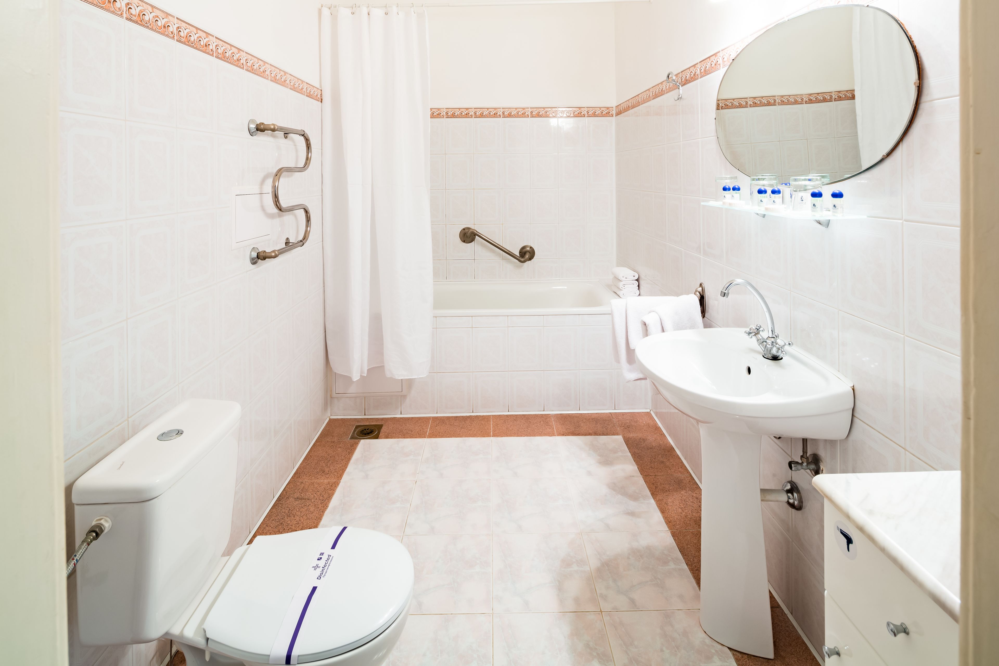A bathroom with a toilet, sink, bathtub, and shower curtain.