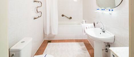 A bathroom with a toilet, sink, bathtub, and shower curtain.