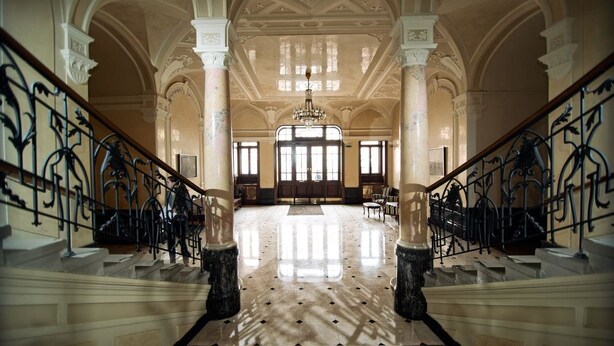 A grand lobby with marble floors, ornate columns, and a chandelier. - George Hotel (Lviv)