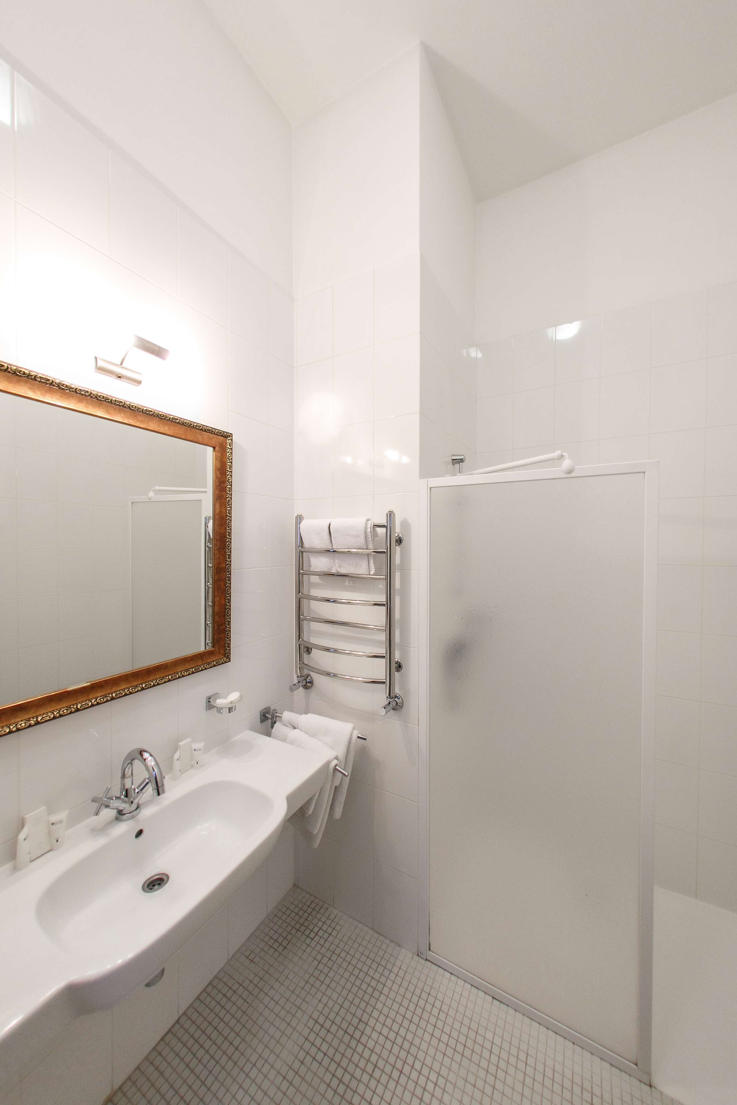 Un bagno con lavandino bianco, specchio e doccia.