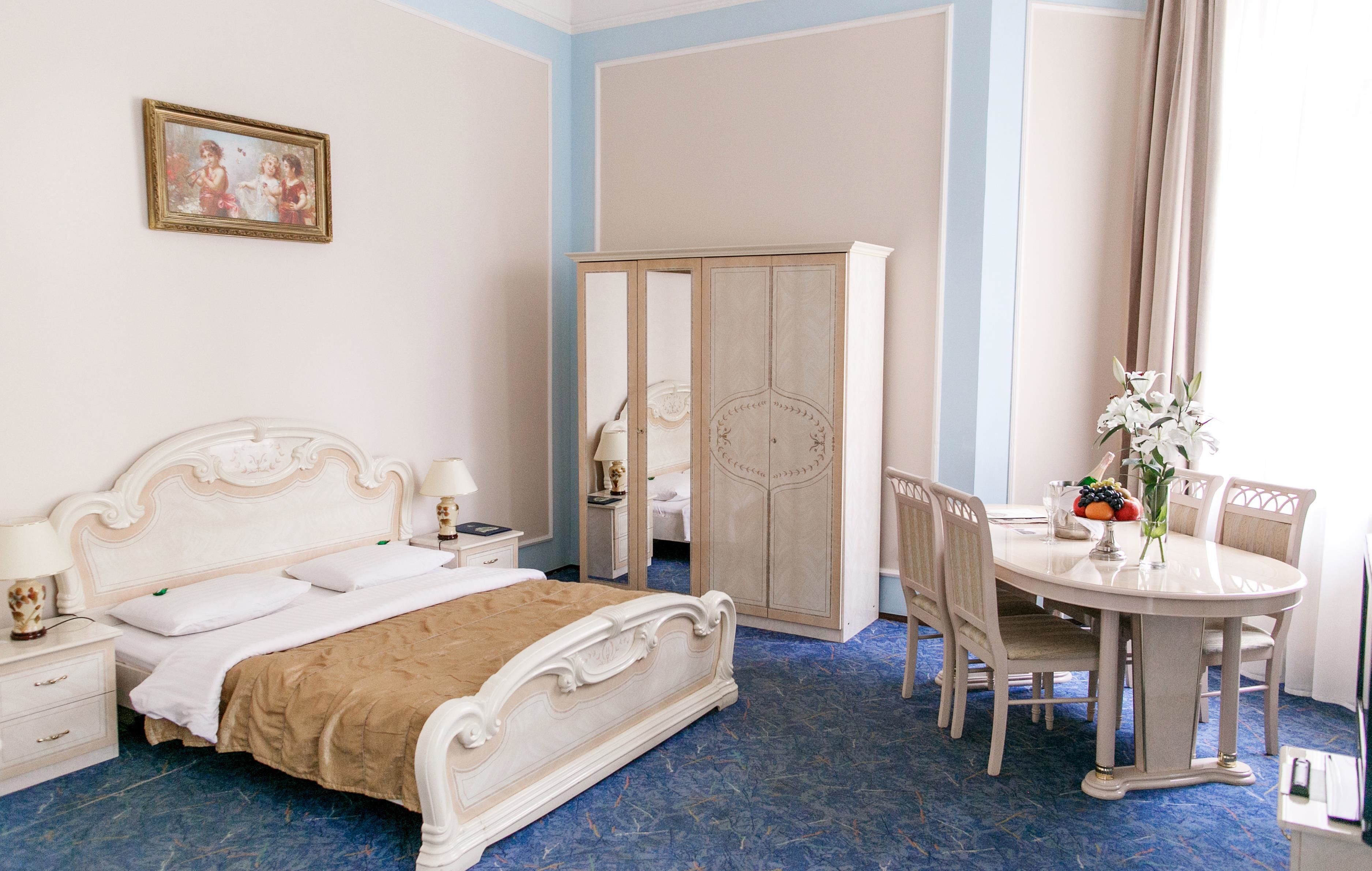 Un dormitorio con cama, mesita de noche, lámpara, cómoda, armario y una mesa de comedor con sillas.