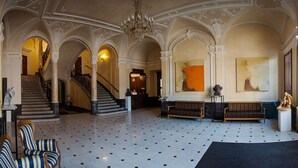 A grand lobby with a marble floor, a staircase, and a reception desk. - George Hotel (Lviv)