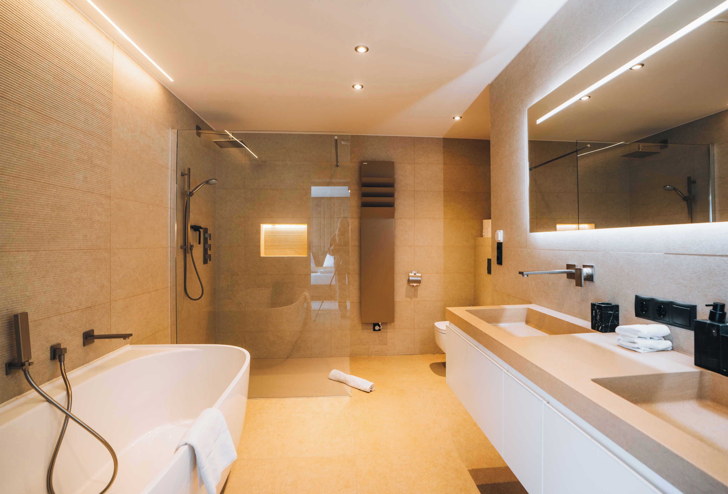 A modern bathroom with a large bathtub, a separate shower area, and a vanity with a mirror.