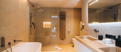 A modern bathroom with a large bathtub, a separate shower area, and a vanity with a mirror.