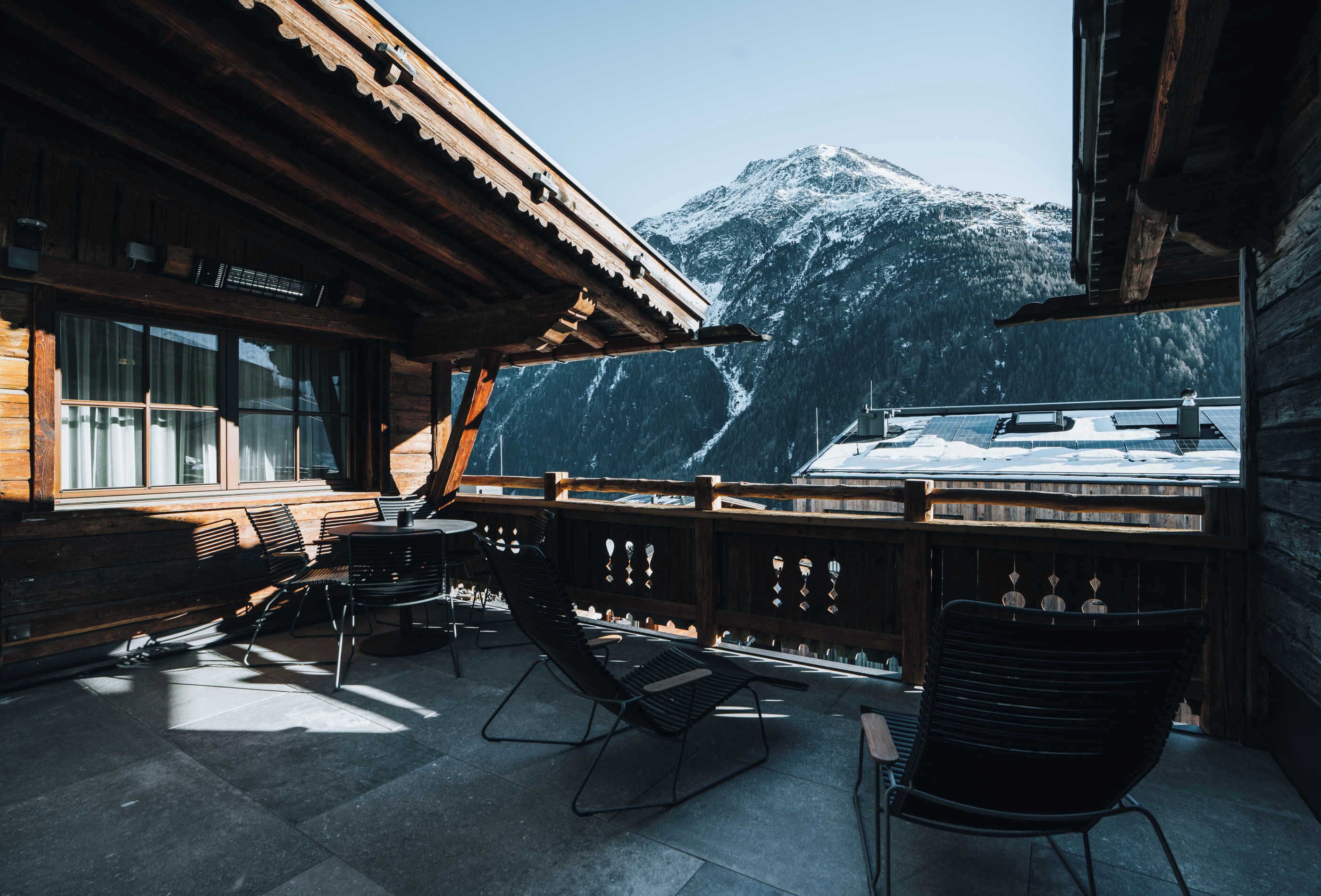 A wooden cabin with a balcony overlooking a snowy mountain.