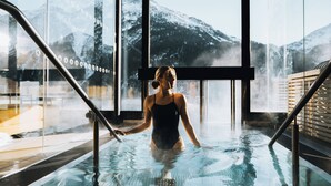 A person in a swimming pool with a view of snow-capped mountains through large windows. - Grünwald Resort (Soelden)