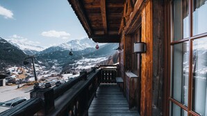 A wooden balcony with a view of a snowy mountain landscape and a cable car in the distance. - Grünwald Resort (Soelden)