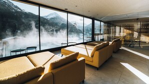 A modern lounge with large windows overlooking a mountainous landscape and a ski lift. - Grünwald Resort (Soelden)