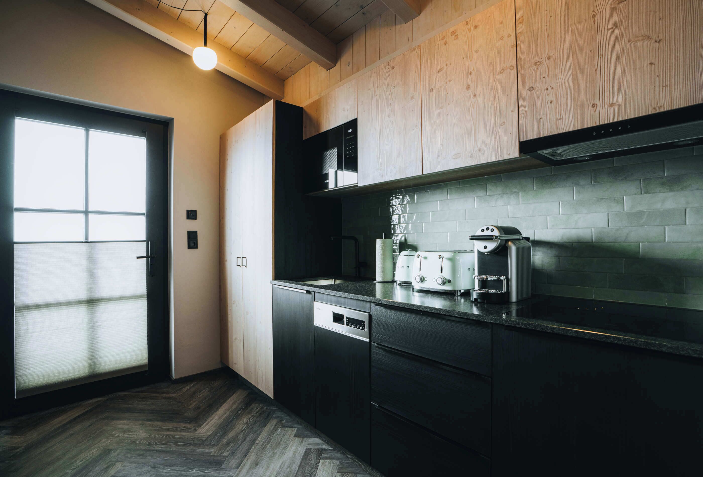 A modern kitchen with wooden cabinets, a black countertop, and a built-in microwave.