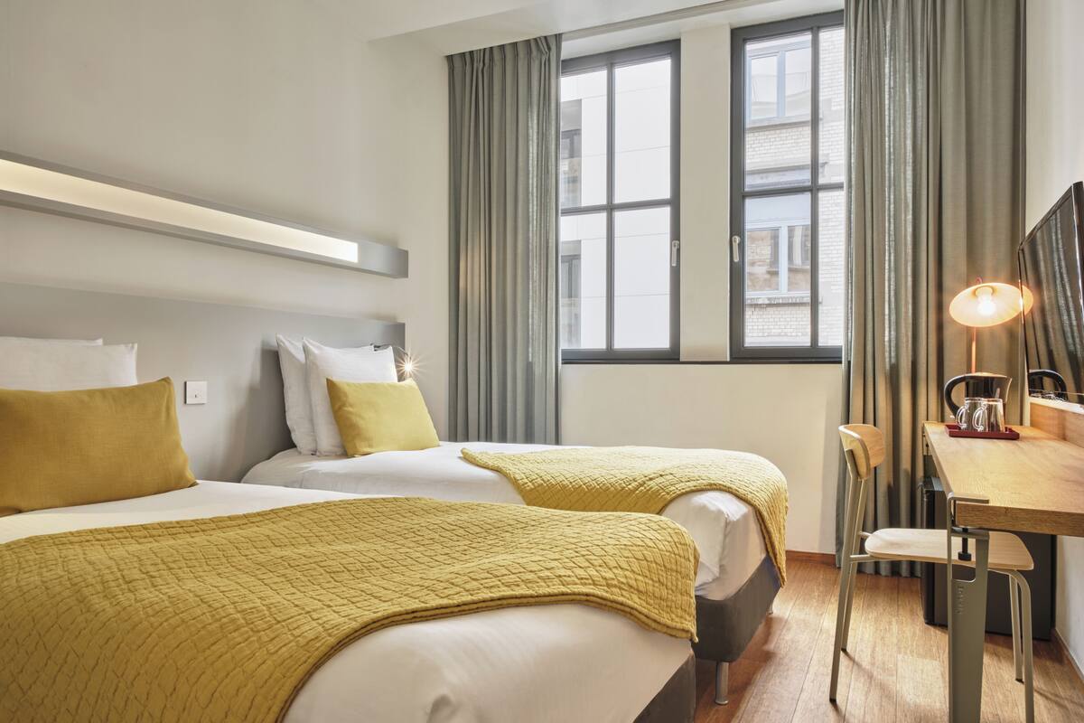 A hotel room with two beds, a desk, and a chair.