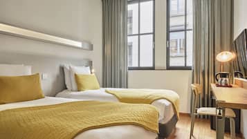 Habitación de hotel con dos camas, un escritorio y una silla.