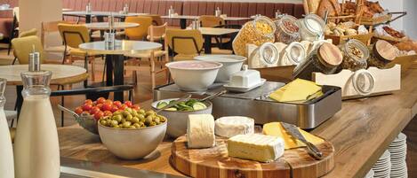 A buffet with various cheeses, meats, and fruits.