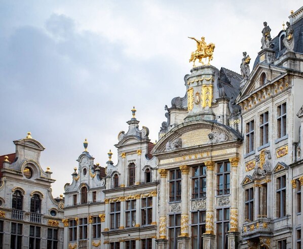 A grand historic building with ornate architecture, including statues and gold accents. - Hôtel Aqua by HappyCulture (Brussels)